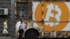Des gens passent devant un panneau portant le logo de Bitcoin dans une rue d'Erevan, en Arménie, le 9 septembre 2019. (REUTERS/Anton Vaganov)
