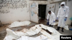Workers pull bags containing bodies of victims of Saudi-led airstrikes on a Houthi detention center, at a hospital morgue in Dhamar, Yemen, Sept. 2, 2019. 