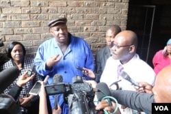 Zimbabwe's Health Minister David Parirenyatwa (right, with glasses), accompanied by local minister Saviour Kasukuwere, talks to journalists after visiting Mbare township, the epicenter of the current typhoid outbreak in Harare, Jan. 2017 (S. Mhofu/VOA). Parirenyatwa has called the lack of hygiene shocking and deplorable.