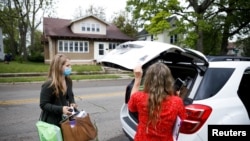 Rocking Horse Community Outreach Worker Amanda Ambrosio (left) and Hadley Smiddy (right) deliver food to a patient in the Purple Apron Program, which provides food, nutrition classes, and a supportive community for patients, in Springfield, Ohio, U.S., May 17, 2021. (REUTERS)
