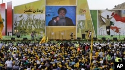 Supporters of Hezbollah leader Hassan Nasrallah watch a broadcast of his speech in Mashghara, Bekaa Valley, Lebanon, May 25, 2013.