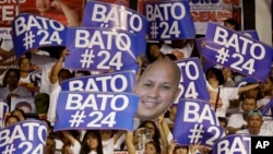 Supporters raise their posters to cheer their senatorial candidate, former national police chief Rogelio "Bato" Dela Rosa during the last campaign rally by the administration for the midterm elections in suburban Pasig city east of Manila, Philippines, Ma