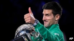 Serbia's Novak Djokovic gestures as he holds the Norman Brookes Challenge Cup after defeating Austria's Dominic Thiem in the final of the Australian Open tennis championship in Melbourne, Australia, Monday, Feb. 3, 2020. (AP Photo/Andy Brownbill)