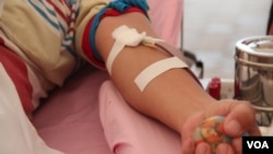 FILE: A blood donor grabs a sponge ball to make the blood flow during a “Give Blood, Give Love” event at Freedom Park in Phnom Penh on 14 February 2015. (Nov Povleakhena/VOA Khmer)