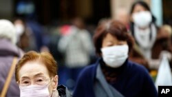 Pedestrians wear protective masks as they walk through a shopping district in Tokyo Thursday, Jan. 16, 2020. Japan's government said Thursday a man treated for pneumonia after returning from China has tested positive for the new coronavirus…