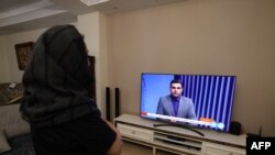 Seorang wanita Iran di Teheran menonton saluran TV berita Iran, yang meliput berita serangan Iran terhadap Israel, Minggu, 14 April 2024. (Foto: Atta Kenare/AFP)