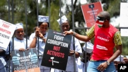 FILE - Demonstrators wear mock prison outfits to show that they want to imprison those engaged in corruption, in Nairobi, Kenya, Nov. 3, 2016. Kenya and Jersey signed a deal Thursday for the return of millions of dollars in graft money.
