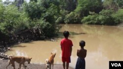 ក្មេង២នាក់ ឈរនៅមាត់ស្ទឹងអន្លង់ក្រូច ក្នុងឃុំប្រម៉ោយ ស្រុកវាលវែង ខេត្តពោធិ៍សាត់ ដែលជាកន្លែងស្ថាបនាទំនប់វារីអគ្គិសនី។ (ស៊ុន ណារិន/VOA)