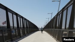 Un solitario peatón cruza el puente de la frontera entre Estados Unidos y México en San Diego, California, el 21 de abril de 2020.