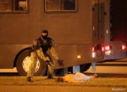 Un policía enmascarado hace señas preguntando qué hacer con un manifestante herido en las protestas tras las elecciones del domingo.