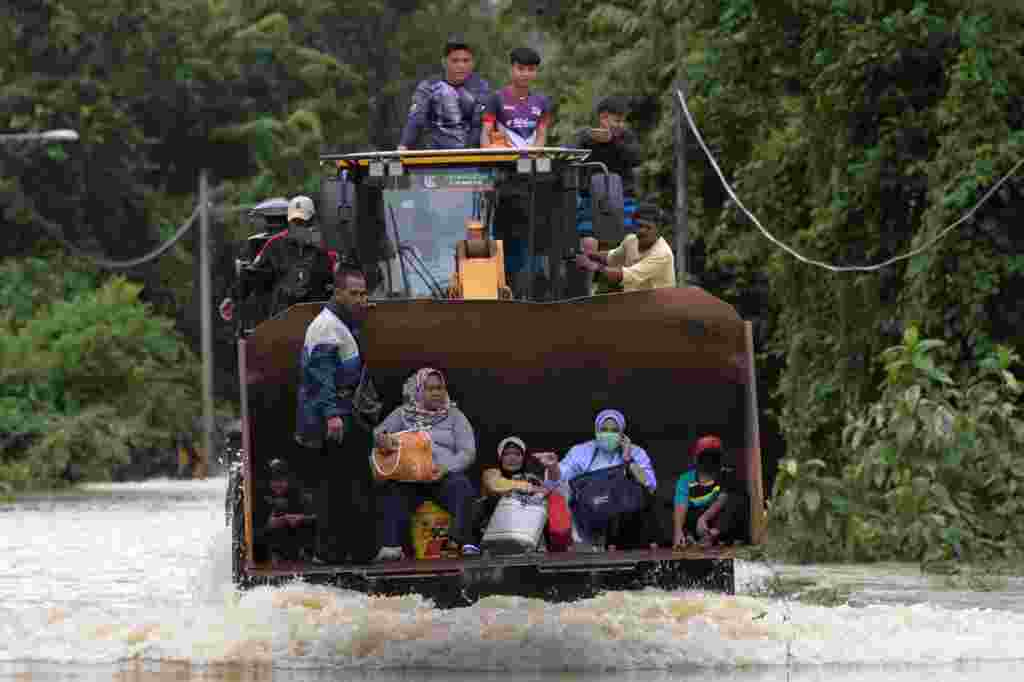 Residents ride a digger vehicle through floodwaters following heavy monsoon downpour in Lanchang, Malaysia's Pahang state.