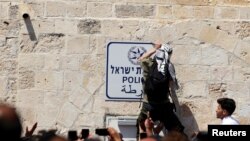 Rai mmoja wa Palestina akiondoa alama kwenye ukuta katika eneo la msikiti wa Al-Aqsa Mosque, kufuatia mapigano na askari wa Israeli huko Old City Jerusalem.