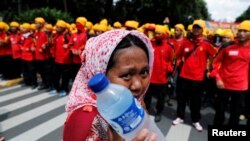 រូបឯកសារ៖ អ្នក​លក់​​ទឹក​ម្នាក់​កំពុង​កាន់​ទឹក​សុទ្ធ​នៅ​ពេល​នាង​ដើរ​នៅ​ជិត​​ក្រុម​មនុស្ស​ប្រមូល​ផ្តុំ​ដើម្បី​ប្រារព​ទិវា​«១ឧសភា» នៅ​មុខ​លំនៅដ្ឋាន​របស់​ប្រធានាធិបតី​ ក្នុង​ទីក្រុង​​ហ្សាការតា ប្រទេស​ឥណ្ឌូនេស៊ី កាល​ពី​ខែ​ឧសភា ឆ្នាំ​២០១៦។