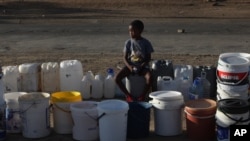 A boy keeps a spot in a queue for free water being transported in by the municipality, in Senekal, South Africa, Jan. 7, 2016.