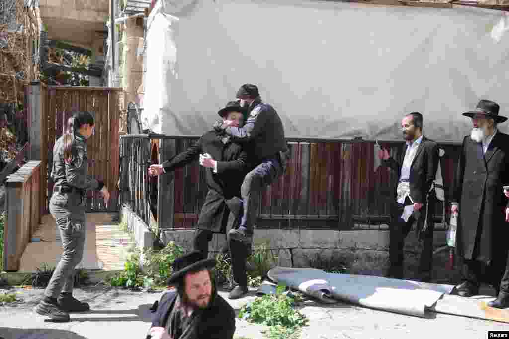 A police officer jumps on a demonstrator's back where Ultra-Orthodox Jewish men are protesting against joining the army, outside the military recruitment bureau in Jerusalem.