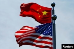 FILE - Chinese and U.S. flags flutter near The Bund before a U.S. trade delegation meets its Chinese counterparts for talks in Shanghai, China, July 30, 2019.