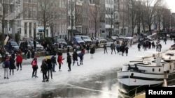 People ice skate during a cold snap across the country at the Prinsengracht in Amsterdam, Netherlands February 14, 2021. (REUTERS/Eva Plevier)
