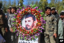 FILE - Military personnel held a photo of Gen. Abdul Raziq, Kandahar police chief, who was killed by a guard, during his burial ceremony in Kandahar, Afghanistan, Oct. 19, 2018.