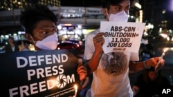 FILE - Protesters light candles while they hold banners, during a rally in Manila, Feb. 10, 2020, when the Philippine government asked the Supreme Court to shut down the country's largest TV network, ABS-CBN Corp., by revoking its operating franchises.