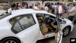 Des enquêteurs et journalistes pakistanais entourent la voiture portant des traces sang du célèbre chanteur soufi Amjad Sabri après l'attaque dont il a été victime à Karachi, au Pakistan, le mercredi 22 juin 2016.