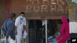 A Kashmiri man tries on a pair of shoes outside a shop in Srinagar, Indian controlled Kashmir, May 16, 2020.