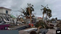 អគារ​ដែល​ត្រូវ​ដួល​រំលំ​ដោយ​និង​ដើមឈើខ្ពស់​ដែល​​បាន​បាក់​ស្រុត​នៅទីក្រុង​ Marigot បន្ទាប់ពីព្យុះ​សង្ឃរា Irma​ បាន​បោក​បក់ កាលពី​ថ្ងៃទី​០៩ កញ្ញា ២០១៧។