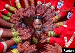 Brides display their hands decorated with henna around a bride as she poses for her own photographer during a mass marriage ceremony in which, according to its organizers, 70 Muslim couples took their wedding vows, in Ahmedabad, India, February 11, 2018.