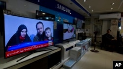 A Pakistani channel broadcasts a report about western couple, seen at a local electronic shop in Islamabad, Pakistan, Thursday, Oct. 12, 2017.