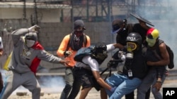 2017 年 4 月 10 日，委內瑞拉加拉加斯，示威者與國民警衛隊衝突時，幫助一名腿部受傷的記者。（美聯社)