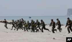 FILE - U.S. and Philippine marines storm the beach to simulate a raid during the joint U.S.-Philippines military exercise at the Naval Training Exercise Command, a former US naval base, and facing the South China Sea at San Antonio township, Zambales province, Philippines.