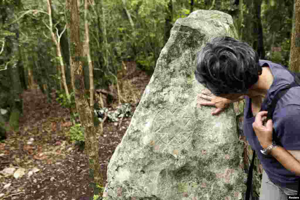 A woman examines an esoteric sign engraved on a rock near the summit of the Peak of Bugarach, the highest point of the Corbieres massif, in southwestern France, June 24, 2011.