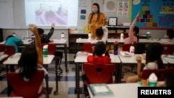 Seorang guru memberikan pelajaran di sebuah sekolah dasar yang dibuka kembali di Chelsea, Massachusetts, AS 15 September 2021.