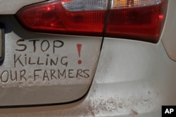 En esta foto de archivo del lunes 30 de octubre de 2017, un letrero en un auto exige el fin de los asesinatos en granjas en Sudáfrica, durante el bloqueo de una autopista en Midvaal, Sudáfrica.