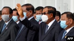 រូបឯកសារ៖ ​លោក​នាយករដ្ឋមន្ត្រី ហ៊ុន សែន (លើក​ដៃឡើង) ឈរ​ជាមួយ​នឹង​មន្ត្រី​កំពូលៗ​របស់​លោក​មួយ​ចំនួន​រួម​មាន​លោកលោក ទៀ បាញ់ និង​លោក ស ខេង ក្នុង​អំឡុងពេល​ជូន​ដំណើរ​ព្រះមហាក្សត្រ​យាង​ចេញ​ដំណើរ​ទៅ​កាន់ប្រទេស​ចិនកាល​ពី​ថ្ងៃទី៦ ខែតុលា ឆ្នាំ២០២០។