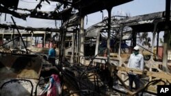 People look at burned-out buses in Lagos, Oct. 24, 2020. Nigeria's president says 51 civilians have been killed in unrest following days of peaceful protests over police abuses, and he blames "hooliganism" for the violence.