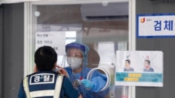 A medical worker in a booth takes a nasal sample from a police officer during coronavirus testing at a makeshift testing site in Seoul, South Korea, Sept. 25, 2021.