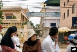 FILE - Cambodians and Muslims ride on a motor-cart past a catholic church in Phnom Penh, Cambodia, Tuesday, July 17, 2007.
