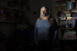 In a photo taken Thursday, April 30, 2020, Jane St. Louis, a grocery store employee, poses for The Associated Press in her home's garage in Damascus, Maryland.