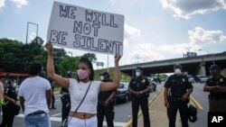 អ្នក​តវ៉ា​ម្នាក់​លើក​ស្លាក​អក្សរ​មួយ​នៅ​មុខ​ប៉ូលិស​កាល​ពី​ថ្ងៃ​សៅរ៍ ទី​១៣ ខែមិថុនា ឆ្នាំ ២០២០ នៅ​ភោជនីយដ្ឋាន​លក់​ម្ហូប Fast foodក្នុង​ទីក្រុង Atlanta ជា​ទី​ដែល​លោកRayshard Brooks ត្រូវ​បាន​ប៉ូលិស​បាញ់​ឲ្យ​ស្លាប់​ កាល​ពី​ល្ងាច​ថ្ងៃ​សុក្រ។