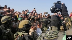 ชาวไทยสองคนซึ่งกลุ่มฮามาสจับเป็นตัวประกันในฉนวนกาซาตั้งแต่วันที่ 7 ตุลาคม 2023 ได้รับการคุ้มกันโดยนักรบฮามาส ขณะที่พวกเขาถูกส่งตัวไปยังกาชาดในเมืองคานยูนิส ฉนวนกาซา ในวันพฤหัสบดีที่ 30 ม.ค. 2025 (AP Photo/Jehad Alshrafi)