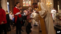 Sacerdotes dan la comunión a los feligreses durante la misa del domingo de Pascua en la grandiosa iglesia Saint-Eustache en París, el domingo 21 de abril de 2019. (AP Foto/Francisco Seco)