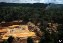 FILE - Helicopters are visible at an illegal mining camp during an operation by Brazil's environmental agency aimed at combating illegal mining in Yanomami Indigenous territory, Roraima state, Brazil, Feb. 11, 2023. (AP Photo/Edmar Barros, File)