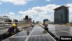 資料照片：中國浙江義烏市國際商貿城的屋頂，工人正在安裝太陽能電池板（2017年7月17日)