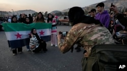 Sirijski opozicioni borac slika građanke koji nose revolucionarnu zastavu dok slave drugi dan nakon što su pobunjeničke snage preuzele Damaska, u Siriji, decembra. 9, 2024.