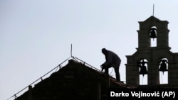 Radnik popravlja krov na crkvi Svete nedelje (Foto: AP/Darko Vojinović)