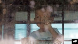 ARCHIVO - Un niño inmigrante mira desde un autobús de la Patrulla Fronteriza de EE.UU. que sale del Centro de Procesamiento Central de la Patrulla Fronteriza de EE.UU. En McAllen, Texas, el 23 de junio de 2018.