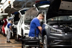 FILE - A worker wears a protective mask at the Volkswagen assembly line after VW re-started Europe's largest car factory after a coronavirus shutdown, in Wolfsburg, Germany, April 27, 2020.