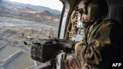 Seorang tentara Taliban di dalam helikopter yang berpatroli di Distrik Barmal, Provinsi Paktika, dua hari setelah serangna udara Pakistan di wilayah itu, 26 Desember 2024. (Foto: Ahmad Sahel Arman/AFP)