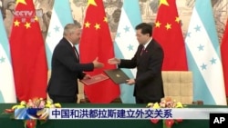 Los cancilleres de Honduras, Eduardo Enrique Reina García, a la izquierda, y el de China, Qin Gang, intercambian acuerdos durante una ceremonia de firma en Beijing, el 26 de marzo de 2023. (CCTV a través de AP)