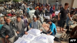 ผู้คนช่วยกันขนกระสอบแป้งที่หน่วยงานผู้ลี้ภัยปาเลสไตน์ของยูเอ็นนำมาแจกจ่าย ให้ที่เมือง เดอีร์ เอล-บาลาห์ ของฉนวนกาซ่า เมื่อ 3 พ.ย. 2567